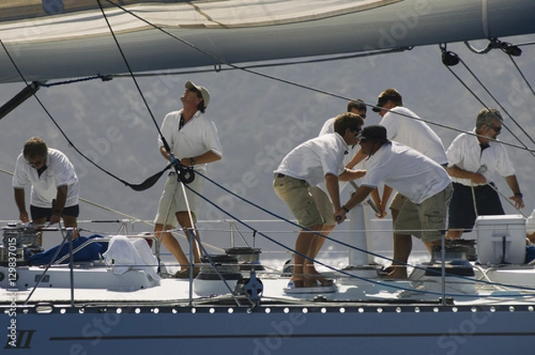 Obraz Side view of crew members working on sailboat