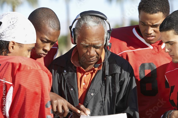 Fototapeta Piłkarze i trener wspólnie omawiają strategię