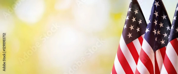 Fototapeta American flags waving gently in soft, warm background evoke sense of patriotism and remembrance