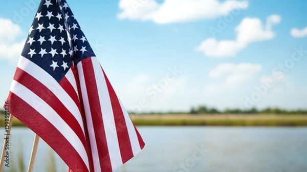 Fototapeta American flag waving by serene lake under blue sky with clouds