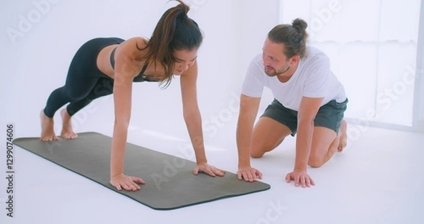 Obraz A personal trainer Coaching guides a woman performing push-ups Exercise on a yoga mat in a bright, minimalist studio environment.