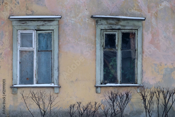 Fototapeta Ветхие окна с деревянными рамами старого жилого дома с потрескавшейся штукатуркой 
