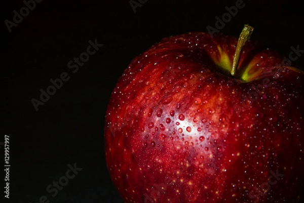 Fototapeta wet red apple in drops of water on a black