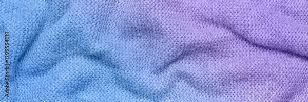 Fototapeta A soft and textured gradient blue and purple knitted fabric with gentle waves and folds, creating a cozy and warm appearance. Ideal for textile backgrounds, fashion, or home decor themes.