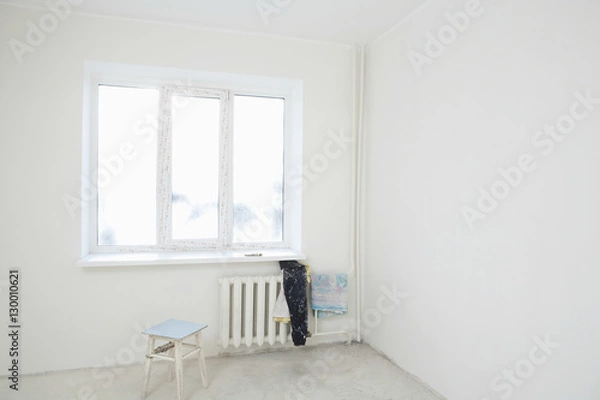 Fototapeta Dirty clothes on radiator under window of new apartment