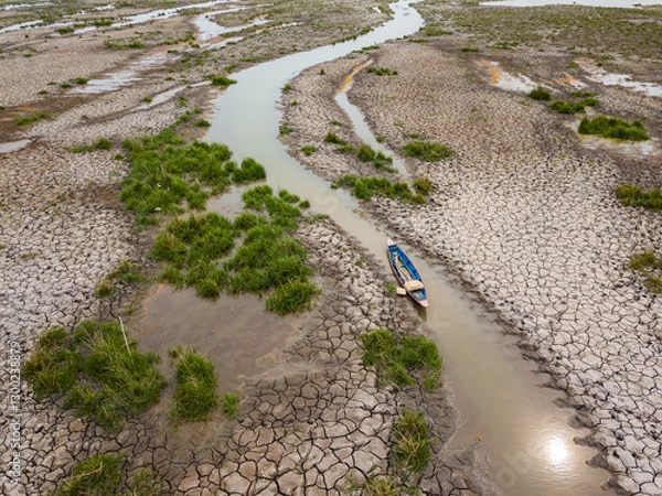 Obraz Boats are moored in a river that is drying up in the summer heat.