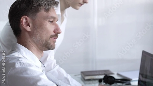 Fototapeta Business colleagues collaborating on a project, reviewing data on a laptop and engaging in productive discussion in a modern office. Business people concept