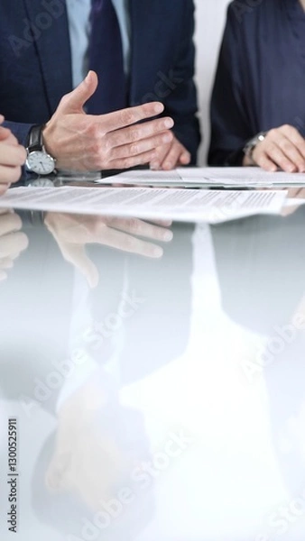 Fototapeta Business people are discussing a contract during meeting while sitting at the glass table in office, vertical close up view. Concept of success and team work