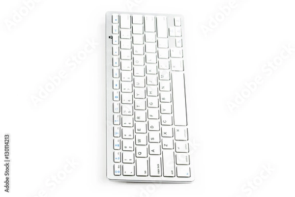 Fototapeta Modern aluminum computer keyboard. Wireless, blue-tooth computer keyboard isolated on white background. Close up of whit, silver  wireless aluminum fingerboard with english letters.Top, side view.
