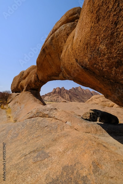 Obraz The iconic Spitzkoppe arch framing the 1728m Spitzkoppe peak in the Namibian desert.
