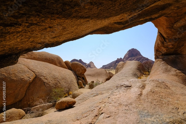 Obraz View from inside the Spitzkoppe arch in Damaraland, Namibia, showcasing smooth granite formations under a clear sky.