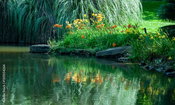 Fototapeta garden vegetation with flowers reflected distorted in still waters of lake water surface