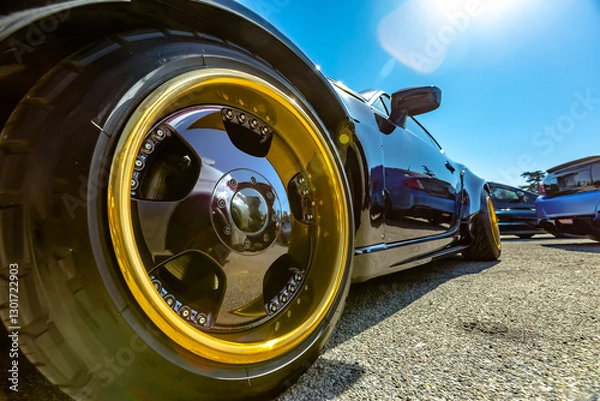 Fototapeta Perspective view of a black car with large golden rims in the front