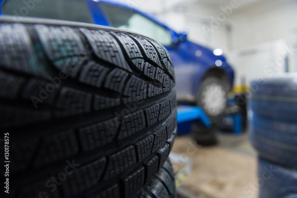 Obraz Detail of a winter tyre with a car in the background