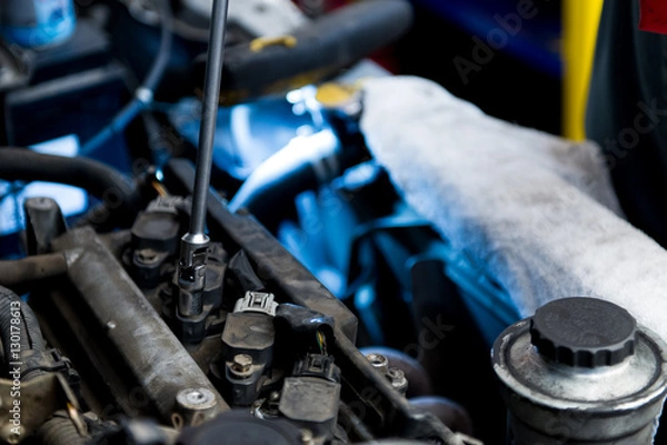 Fototapeta Mechanic fixing a car's engine with a wrench