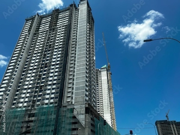 Fototapeta A building under construction, with scaffolding wrapping around the structure, showcasing ongoing progress, skyscrapers in the city