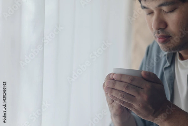Obraz A young man is drinking a cup of coffee.