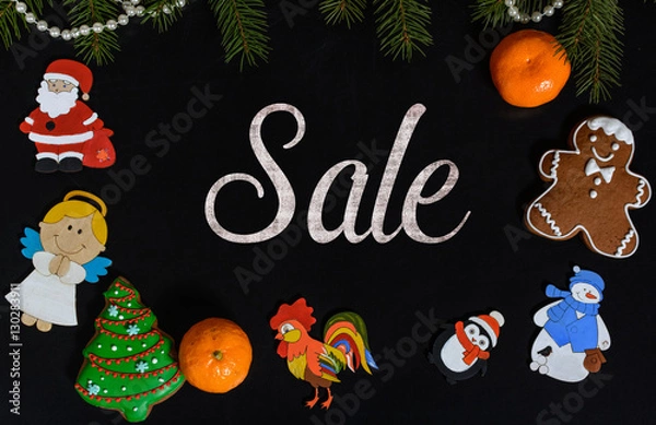 Fototapeta Xmas composition with text Sale on school blackboard and the Christmas decorations, toys (Santa Claus, Angel, a rooster, a snowman, a penguin) and tangerine