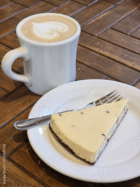 Obraz Delicious cheesecake slice on plate beside cup of coffee, creating cozy cafe atmosphere. Enjoy rich flavors and warm ambiance