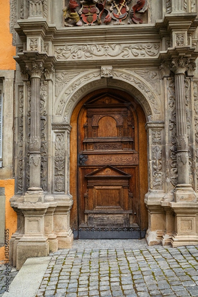 Obraz Ornate wooden door with stone archway and columns. Architectural detail, historical building. European architecture, cobblestone ground, decorative carving.