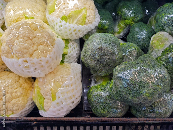 Fototapeta Fresh Cauliflower and Broccoli in Plastic Wrap on Store Display