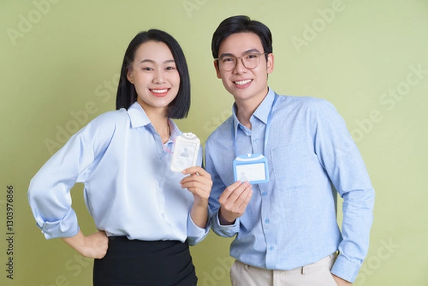Obraz Young professionals posing with name badges in a bright green environment during a networking event