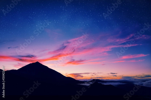 Fototapeta Sylwetka wulkanu del Teide na tle zachodzącego słońca. Góra Pico del Teide w Parku Narodowym El Teide w nocy. Nocny krajobraz z drogą mleczną na niebie. Teneryfa, Wyspy Kanaryjskie, Hiszpania