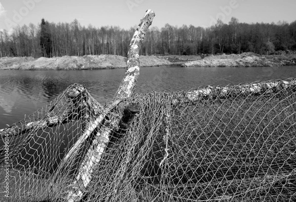 Fototapeta Fishing net on lake shore in black and white style.