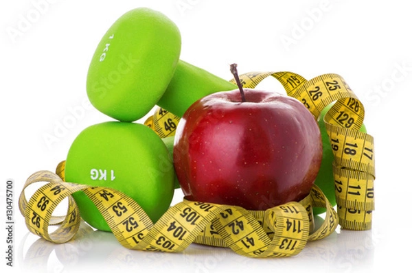 Fototapeta Two dumbbells, red apple, measuring tape.