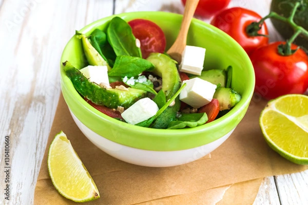 Fototapeta Green salad with avocado, tomatoes, spinach, lime and spices