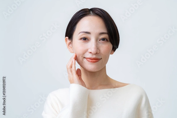 Fototapeta 白背景で肌に触れ微笑むショートヘアーの女性