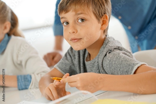 Obraz Portrait of pupil in school class taking notes during writing lesson