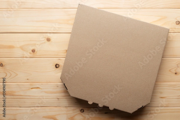 Fototapeta Pizza closed carton box on natural wooden table flat lay mockup with copy-space