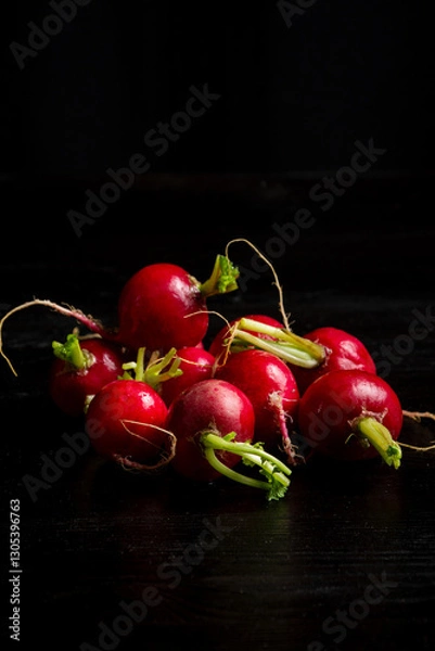 Fototapeta Top view of radishes on table and black background, vertical with copy space