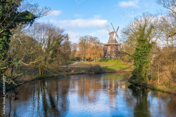Obraz An idyllic pond surrounded by trees and a traditional windmill on a gentle hill