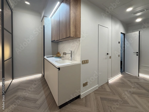 Obraz A contemporary apartment interior showcases a spacious layout with sleek wooden flooring and modern lighting fixtures. The kitchen area features minimalist cabinetry for a clean look.