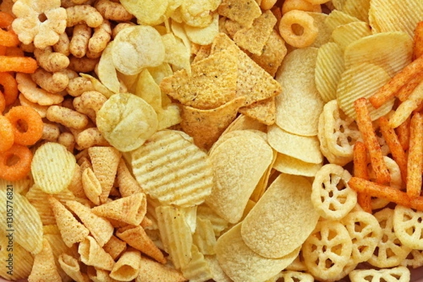 Fototapeta Colorful mix of salty snacks for beer varieties: chips and pretzels, onion rings and crackers. Non-healthy junk food background	