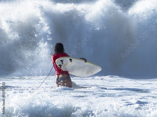 Obraz Girl practicing in the waves of the Atlantic ocean surfing, in f