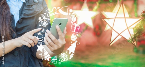 Obraz Woman's hand using smartphone and Christmas icon