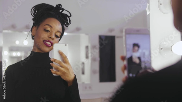 Fototapeta Beauty model photographing its reflection in makeup mirror on mobile phone