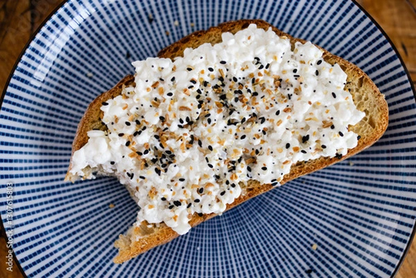 Fototapeta slice of sourdough toast on a blue ceramic plate topped with cottage cheese and everything bagel spice