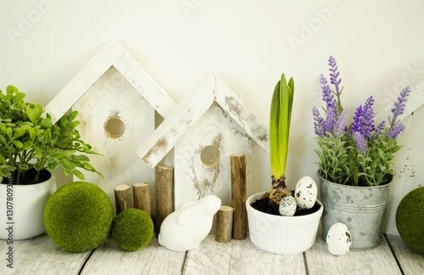 Obraz Easter decorative composition, home decoration for the holiday of bright Easter. On the table are cute rabbits and wooden houses, front view.
