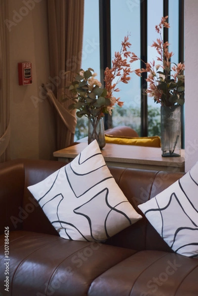 Fototapeta Comfortable sectional sofa adorned with various  white striped throw pillows. Contemporary home with furniture. Pillows on sofa. Artistic and comfortable elements in beautifully decorated hotel lobby.