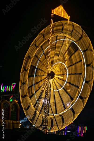 Obraz Intentional camera movement, slow shutter , blur image of giant Ferris wheel illuminated and spinning at night in a funfair.