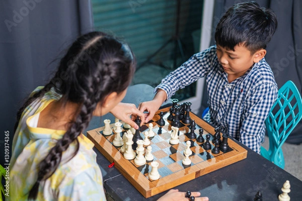 Fototapeta Smart kids enjoying a board game, making their next move in a friendly chess match.