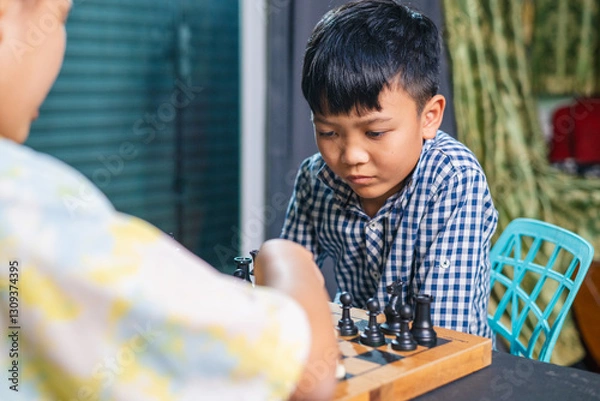 Fototapeta Smart kids enjoying a board game, making their next move in a friendly chess match.