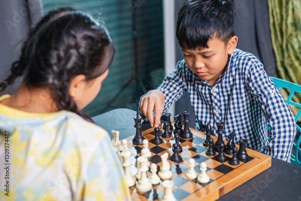 Fototapeta Smart kids enjoying a board game, making their next move in a friendly chess match.