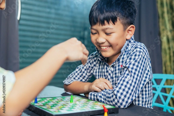 Fototapeta Smart kids enjoying a board game, making their next move in a friendly chess match.