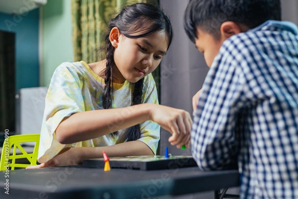 Fototapeta Smart kids enjoying a board game, making their next move in a friendly chess match.