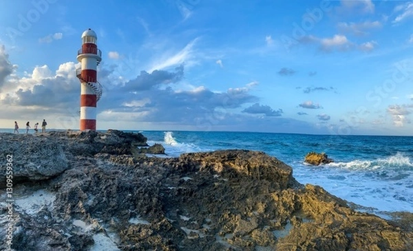 Fototapeta Red and white lighthouse standing on rocks on a beach in Cancun Mexico